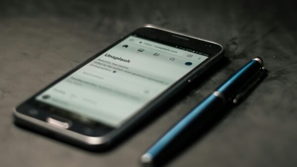 black smartphone beside pen